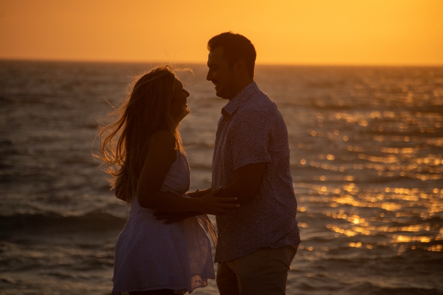 Backlit couple embracing on the beach at golden hour